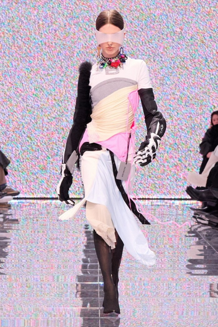 A model in tinted shades covering her eyes and a dress made of pink, beige and white swathes of fabric