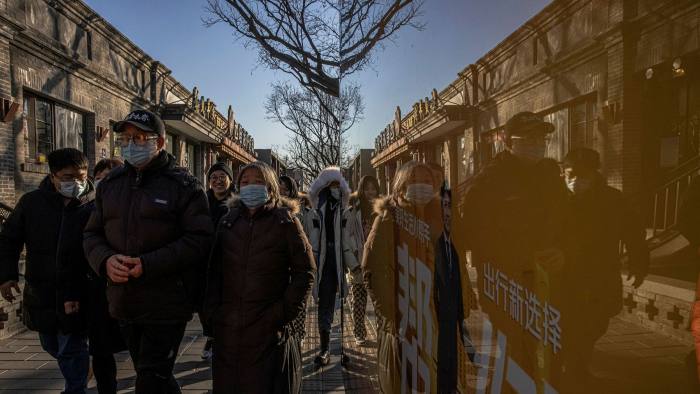 People wearing face masks walk on a street in the Hutong neighbourhood in Beijing