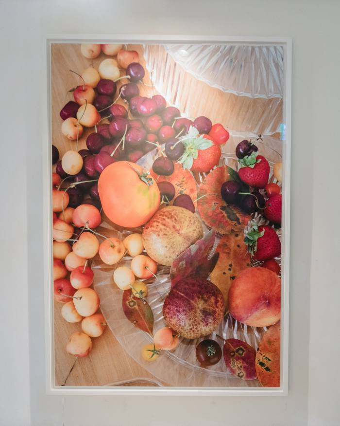A detailed photograph shows an array of fruits on glassware on a wooden surface 