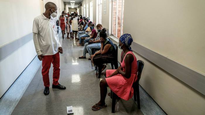 A hospital worker ensures people practise social distancing as they wait in line to get vaccinated against Covid-19 near Johannesburg in South Africa