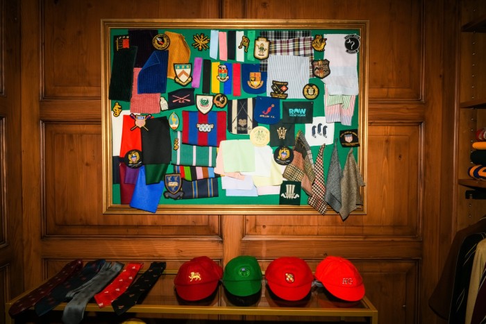 gorras e insignias exhibidas en un estante de madera y en un tablero en una pared de madera
