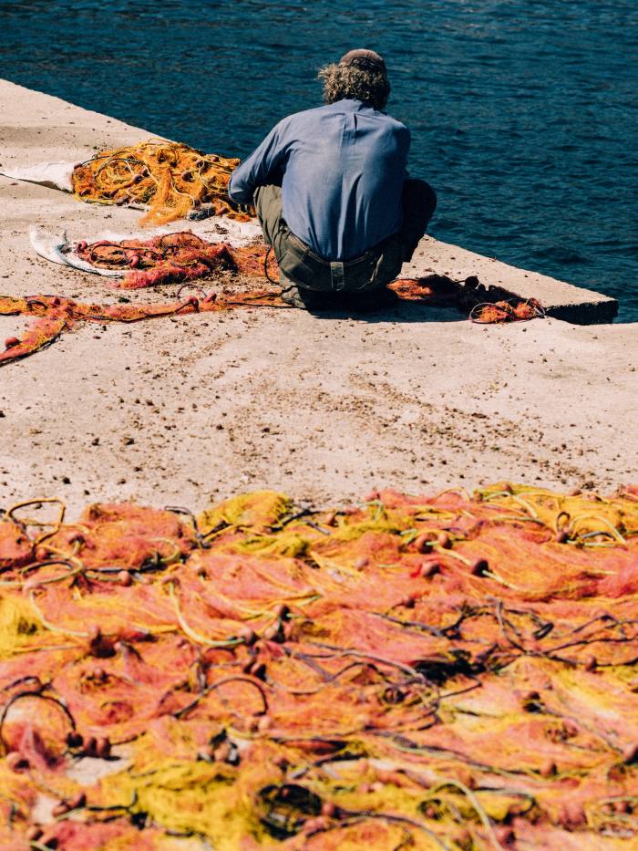 A fisherman mending nets at Xilokeratidi harbour