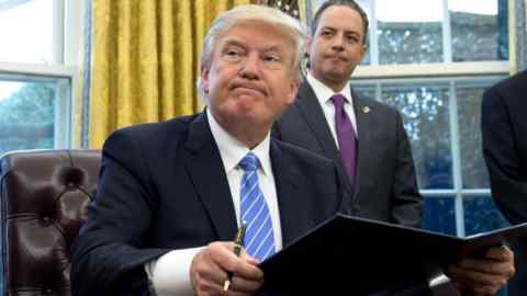 TOPSHOT - US President Donald Trump signs an executive order as Chief of Staff Reince Priebus looks on in the Oval Office of the White House in Washington, DC, January 23, 2017.
Trump on Monday signed three orders on withdrawing the US from the Trans-Pacific Partnership trade deal, freezing the hiring of federal workers and hitting foreign NGOs that help with abortion. / AFP PHOTO / SAUL LOEBSAUL LOEB/AFP/Getty Images