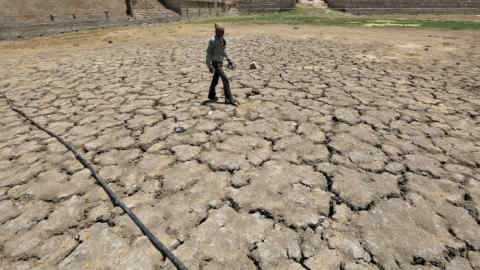 A man walks through a dried-up Sarkhej lake on a hot summer day in Ahmedabad, India, April 21, 2016. Picture taken April 21, 2016. REUTERS/Amit Dave - RTX2B5C5