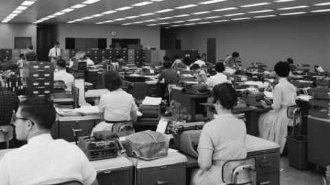 1960s BACK VIEW OF MEN AND WOMEN AT TYPEWRITERS (Photo by H. Armstrong Roberts/ClassicStock/Getty Images)