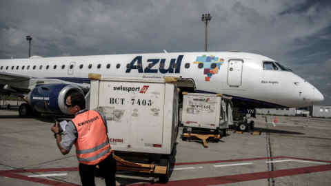 A ground crew member pulls a cart of baggage from an Azul Linhas Aereas Brasileiras SA jet at Viracopos International Airport in Campinas, Brazil, on Wednesday, Sept. 9, 2015