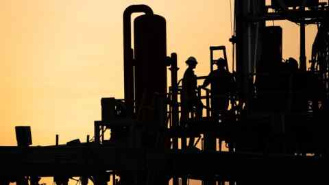 Oil men work on a new oil rig at sunset in the desert oil fields of Sakhir, Bahrain, Sunday, Aug. 3, 2014. (AP Photo/Hasan Jamali)