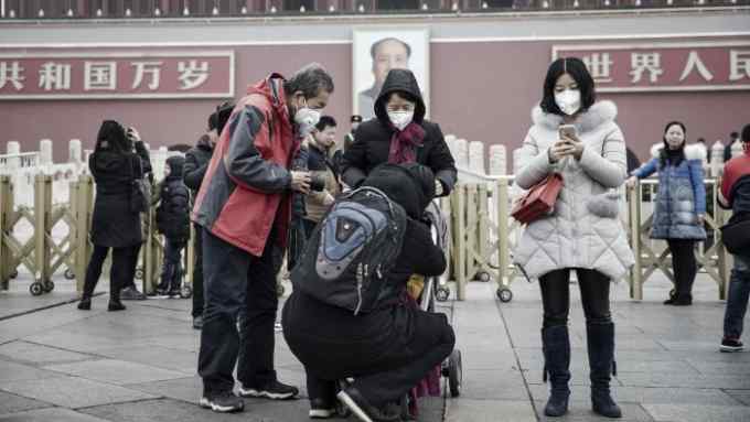 People wearing face masks stand in front of the Tienanmen Gate in Beijing, China, on Friday, Jan. 6, 2017. Toxic haze that settled over much of China during the last three weeks has triggered a flight reflex among residents, leading to the rising popularity of smog avoidance travel packages to far-flung locations such as Iceland and Antarctica. Photographer: Qilai Shen/Bloomberg