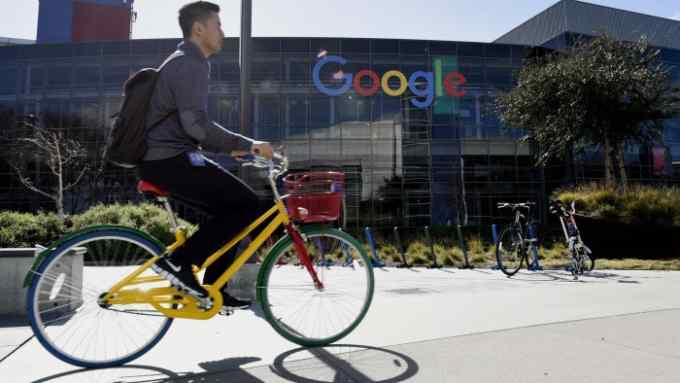 Views Of The Googleplex Campus As Google Inc. Brings Ultra-Fast Internet Access To San Francisco...A cyclist rides past Google Inc. offices inside the Googleplex headquarters in Mountain View, California, U.S., on Thursday, Feb. 18, 2016. Google, part of Alphabet Inc., plans on tapping into existing fiber networks in San Francisco to deliver ultra-fast internet access across the city. Photographer: Michael Short/Bloomberg