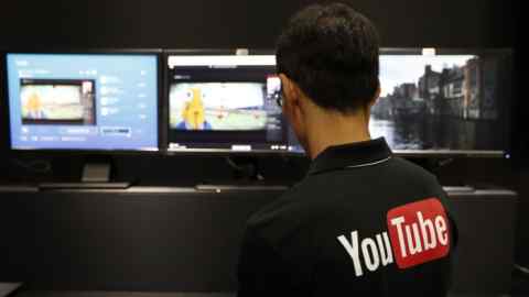 An attendant prepares computers in YouTube Inc. booth at the Tokyo Game Show 2015 at Makuhari Messe in Chiba, Japan, on Thursday, Sept. 17, 2015. There will be record attendance at this year's show with 473 vendors, including more than half from abroad, as of Sept. 1, according to organizers. Photographer: Tomohiro Ohsumi/Bloomberg