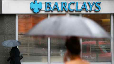 FILE PHOTO: Pedestrians shelter under umbrellas as they walk past a Barclays branch in central London May 8, 2014. REUTERS/Stefan Wermuth/File Photo
