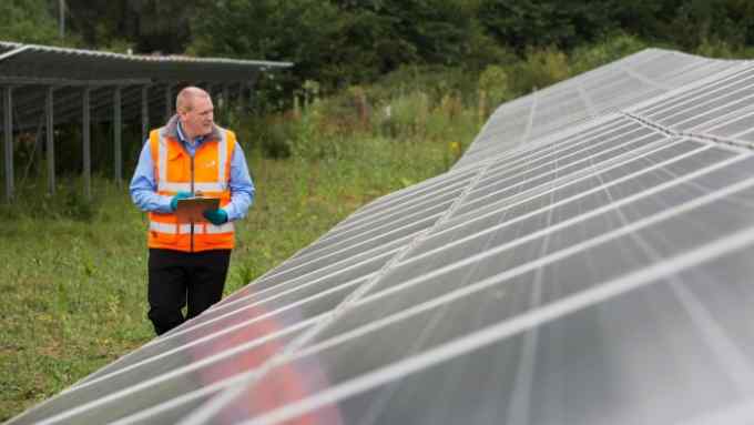 Gavin Naylor water recycling treatment manager inspects the Solar array at Anglian Water's Bedford Water Recycling Center. Credit: David Parry/ FT