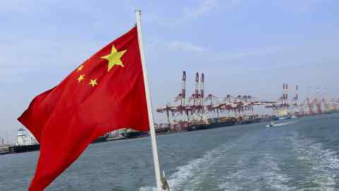 A Chinese flag flies on a vessel moving past the Tianjin Port (Group) Co. Ltd. docks in Tianjin, China, on Wednesday, Sept. 12, 2012. The Chinese government is trying to meet a 7.5 percent economic growth target set in March, which would already be the weakest expansion since 1990. Photographer: Nelson Ching/Bloomberg