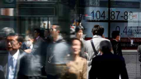 FILE PHOTO: People walk past an electronic board showing exchange rate between Japanese Yen and U.S. Dollar outside a brokerage at a business district in Tokyo, Japan, March 23, 2018. REUTERS/Toru Hanai/File Photo GLOBAL BUSINESS WEEK AHEAD