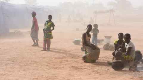 Displaced people, who fled from attacks of armed militants in Roffenega, are engulfed in dust as they sit at the camp built by the German Ngo HELP in Pissila, Burkina Faso January 24, 2020. Picture taken January 24, 2020. REUTERS/Anne Mimault - RC21PE9QXMHB