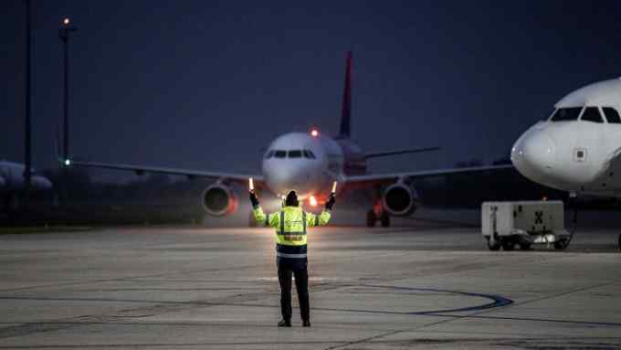 A member of ground crew directs a Wizz Air Holdings Plc passenger aircraft to the gate at Debrecen International Airport in Debrecen, Hungary
