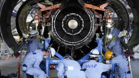 Workers perform maintenance work to a jet engine
