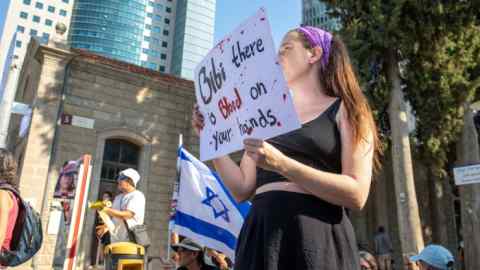 A protester holds a sign saying “Bibi, you have blood on your hands” in a demonstration of support for the families of those kidnapped by Hamas, near the Ministry of Defense in Tel Aviv