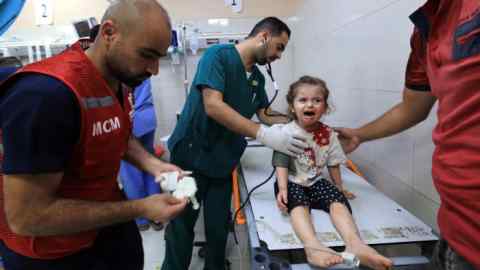 Una ragazza ferita piange mentre è seduta su un lettino da visita all'ospedale Nasser mentre un infermiere si prende cura di lei