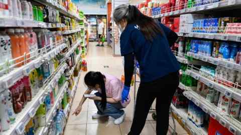 Workers check products’ prices at a supermarket in Beijing