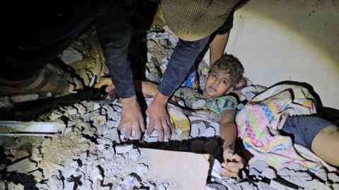 Palestinians work to rescue a boy trapped in rubble