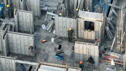 Workers install aluminum alloy formwork for house construction at a construction site