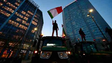 A farmer stands on a tractor at a protest in the centre of Milan