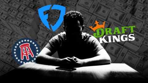 A person with their face in shadow sits hunched over against a background of sports betting sites logos