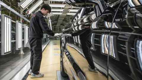 A worker next to a new car at the quality control station of a Chinese production line