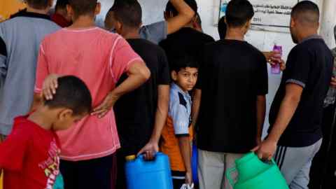 Palestinians gather to collect water in Khan Younis in the southern Gaza Strip, after Israel cut off water supplies to the area