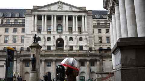 Een voetganger met een paraplu loopt langs het gebouw van de Bank of England