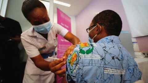 A nurse wearing a facemask vaccinates a man in a Ghana hospital