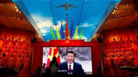 I visitatori si trovano di fronte a uno schermo gigante che mostra il presidente Xi Jinping accanto a una bandiera del partito comunista cinese in un museo militare a Pechino