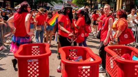 Lidé v červených tričkách Target táhnou během průvodu Gay Pride velké plastové nákupní vozíky
