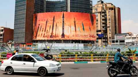 Motorists drive past a billboard depicting Iranian ballistic missiles in central Tehran